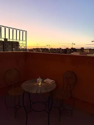 a table and chairs on a balcony with the sunset at Charming Bohemian hideaway in Marrakech in Marrakech