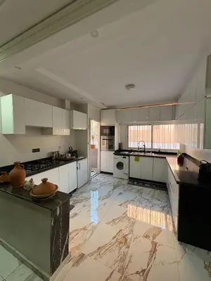 a large kitchen with white cabinets and a marble floor at Appartement plein centre marrakech p in Marrakech