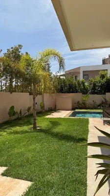 a backyard with a palm tree and a swimming pool at Exceptional Villa Noria Golf in Marrakech