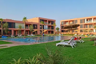 a resort with a pool with chairs and an umbrella at Noria Modern & Cozy Piscine in Marrakech