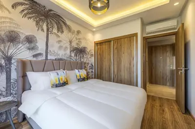 a bedroom with a white bed with palm trees on the wall at Noria Modern & Cozy Piscine in Marrakech