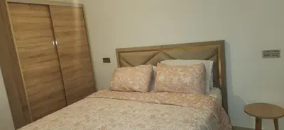 a bedroom with a bed with a wooden headboard and a table at Appartement Serein 10 min jamaa el fnaaa in Marrakech