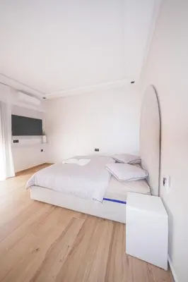 a white bedroom with a bed and a table at Modern apartments, cozy residence, swimming pools in Marrakech