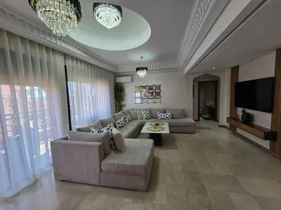 a large living room with a couch and a tv at Appartement de Luxe Piscines et Jardins in Marrakech
