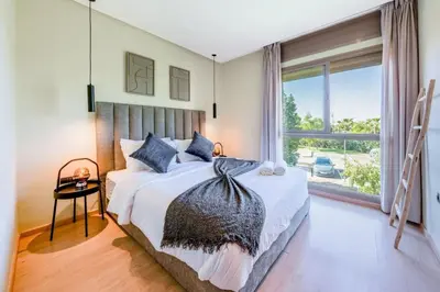 a bedroom with a bed and a large window at Luxueux Appartement rez-de-chaussée Noria Golf in Marrakech