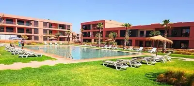 a pool with chairs and umbrellas next to a building at Luxueux Appartement rez-de-chaussée Noria Golf in Marrakech