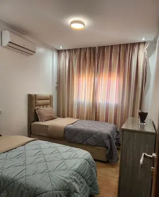 a bedroom with two beds and a window with curtains at Chic Urban Retreat Bright Apartment in Targa in Marrakech