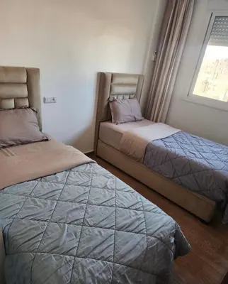 two beds in a bedroom with a window at Chic Urban Retreat Bright Apartment in Targa in Marrakech