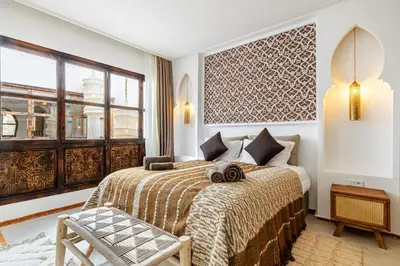 a bedroom with a bed and a chair and a window at Riad Tigmmi - Exclusive - Pool - Free BF - 10 pax in Marrakech