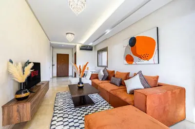 a living room with a couch and a tv at Familial appt-Prestigia- 2BR-Pool-Free parking in Marrakech