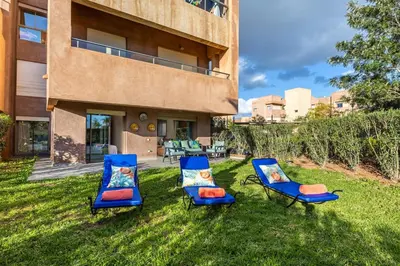 three chairs sitting in the grass in front of a building at Familial appt-Prestigia- 2BR-Pool-Free parking in Marrakech