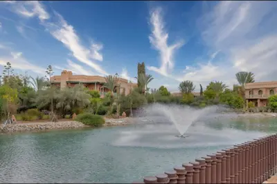 a fountain in a pond in front of a building at Luxe & calme Palmeraie terrasse piscine in Marrakech