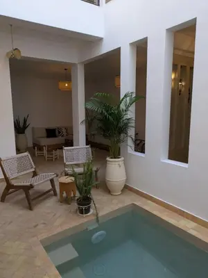 a pool in a living room with chairs and plants at Riad privatif Les Tamaris in Marrakech