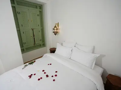 a white bed with flowers on it in a bedroom at Riad privatif Les Ibéris in Marrakech