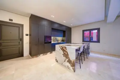 a kitchen with a marble counter and a bar with stools at Plaza Marrakech Comfort Stay in Marrakech