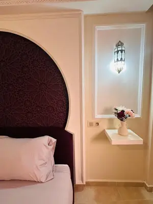 a bedroom with a bed and a window and a vase with flowers at Suite Amethyste - Majorelle in Marrakech