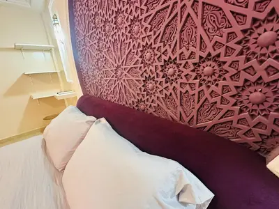 a bedroom with a bed with a red wall at Suite Amethyste - Majorelle in Marrakech