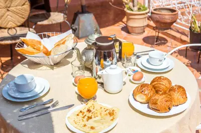 a table with a breakfast of croissants and orange juice at Hotel Atlas in Marrakech