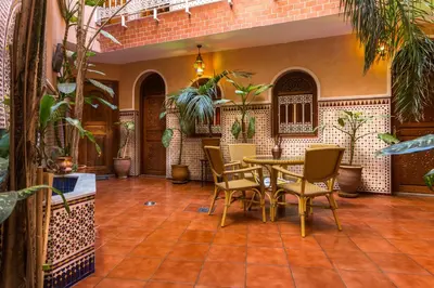 a patio with a table and chairs and plants at Hotel Atlas in Marrakech