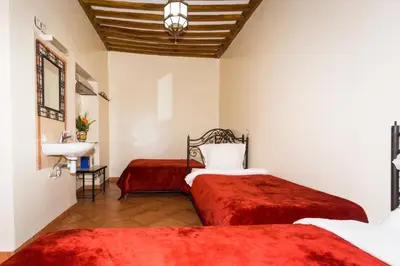 a bedroom with two beds and a sink in a room at Hotel Atlas in Marrakech