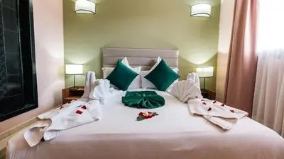 a bed with white blankets and flowers on it at Oliva Hotel Condominium Marrakech in Marrakech