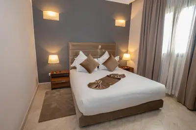 a bedroom with a bed with white sheets and pillows at Oliva Hotel Condominium Marrakech in Marrakech