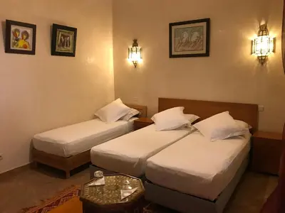 a hotel room with two beds and a table at Dar Tasnime in Marrakech
