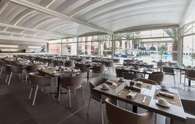 a dining room with tables and chairs and windows at Savoy Le Grand Hotel Marrakech in Marrakech