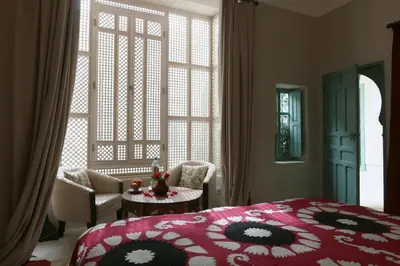a bedroom with a bed and a chair and a table at Riad Dar Ayur in Marrakech