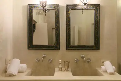 a bathroom with two sinks with mirrors and towels at Riad Dar Ayur in Marrakech