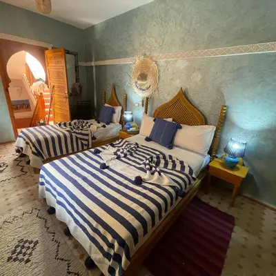 a bedroom with two beds with blue and white stripes at Riad Jenan Adam in Marrakech