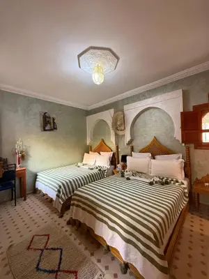 a bedroom with two beds with striped sheets at Riad Jenan Adam in Marrakech