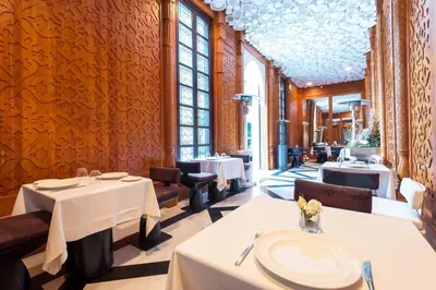 a restaurant with white tables and chairs and windows at Riad Elisa & Spa in Marrakech