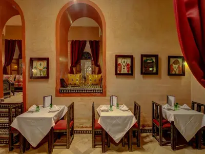a restaurant with two tables and chairs and a mirror at Palais Tinmel Marrakech in Marrakech
