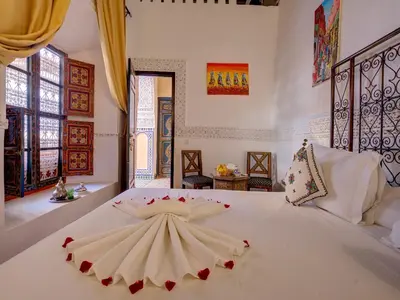 a bedroom with a large white bed with roses on it at Palais Tinmel Marrakech in Marrakech