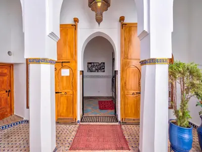 a hallway with wooden doors and a red rug at Palais Tinmel Marrakech in Marrakech