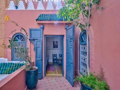 an entrance to a pink house with blue doors at Palais Tinmel Marrakech in Marrakech