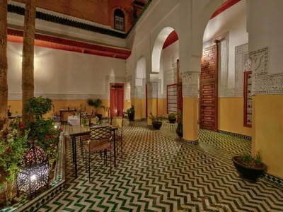 a lobby with tables and chairs in a building at Palais Tinmel Marrakech in Marrakech
