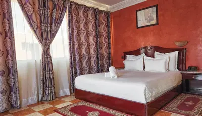 a bedroom with a bed with red walls and curtains at Hôtel Les Ambassadeurs in Marrakech