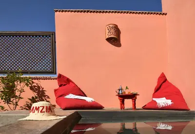 a wall with red pillows and a table and a mask at Riad Lamzia in Marrakech