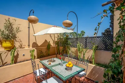 a table with chairs and an umbrella on a patio at Riad Sun of Kech in Marrakech