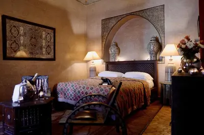 a bedroom with a bed and a chair in a room at Riad Noir d'Ivoire in Marrakech