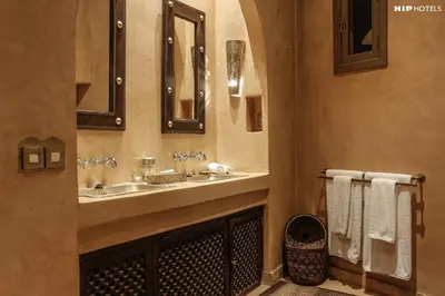 a bathroom with a sink and a mirror and towels at Riad Noir d'Ivoire in Marrakech