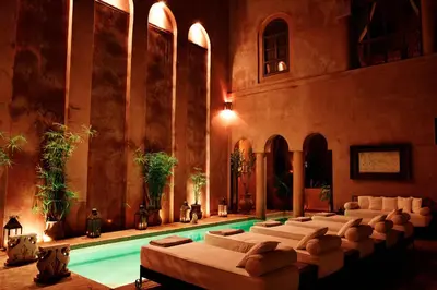 a group of beds in a room with a pool at Riad Noir d'Ivoire in Marrakech
