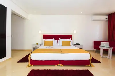 a bedroom with a large bed with yellow and red pillows at Hôtel Racine in Marrakech