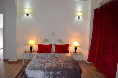 a bedroom with a bed with red pillows and two lamps at Riad Hôtel Essaouira in Marrakech