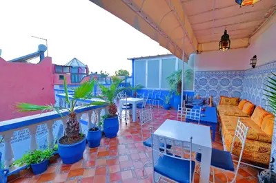 a rooftop patio with a couch and tables and plants at Riad Hôtel Essaouira in Marrakech