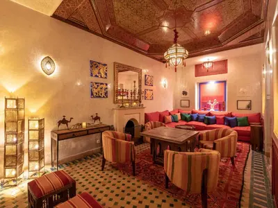 a living room with a red couch and a fireplace at Riad Passali in Marrakech