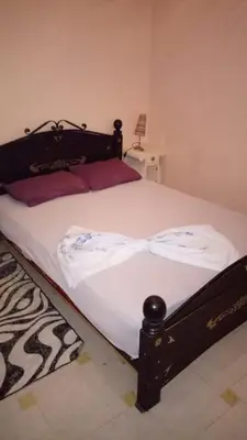 a bed with a black frame and white sheets at Studio meublé proche du centre ville in Marrakech