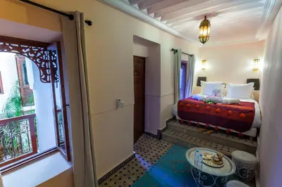 a bedroom with a bed with a table and a window at Riad Chams Marrakech in Marrakech